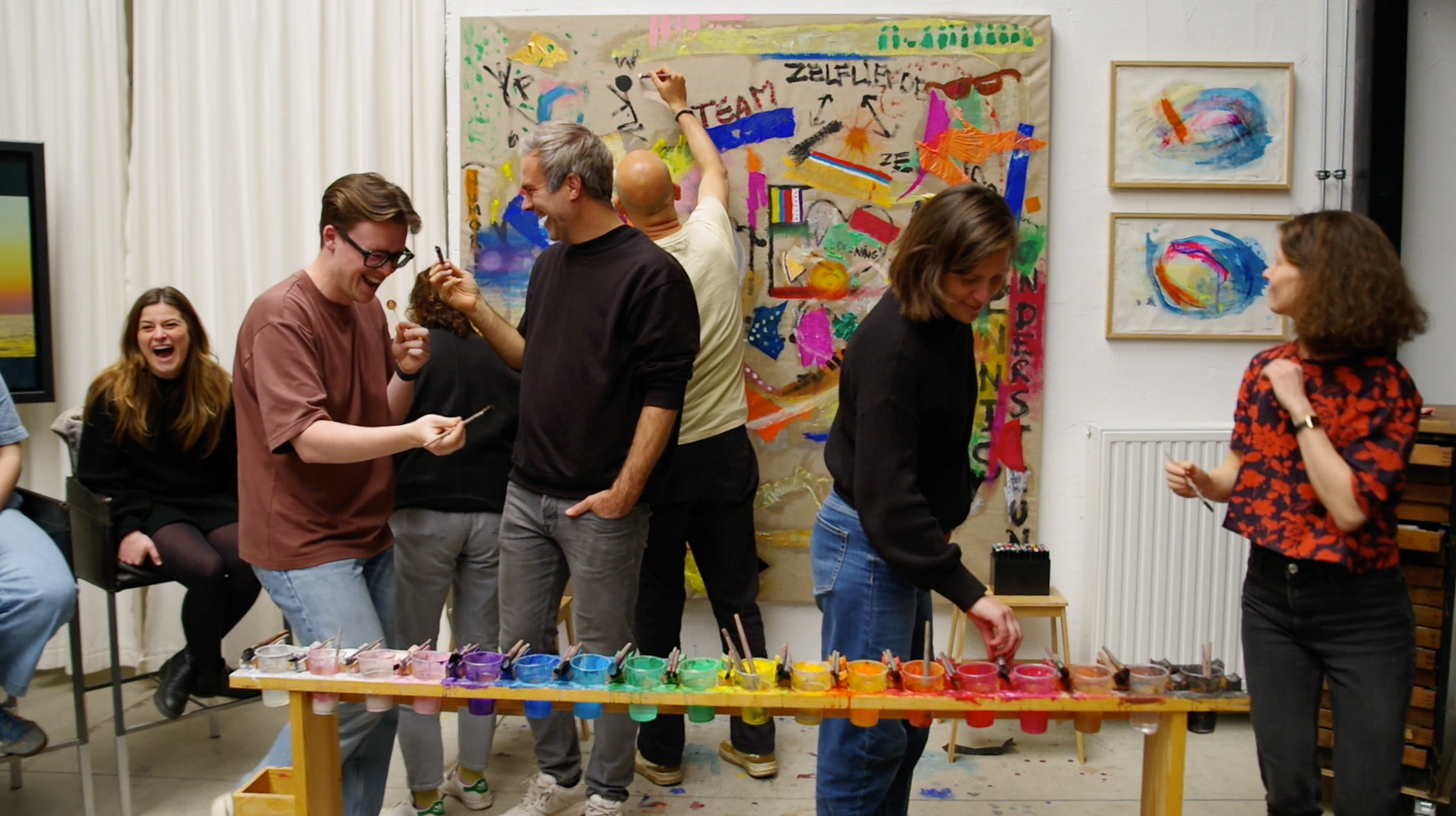 People entering a shared creative process around a large working surface.