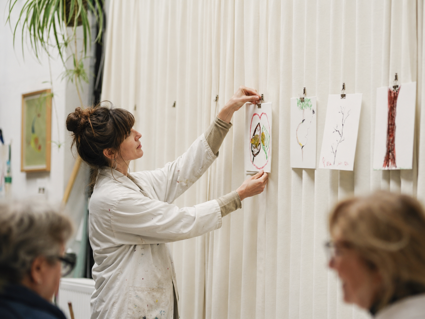 Nicky pinning a participant's work onto the studio curtain during a shared reflection moment.
