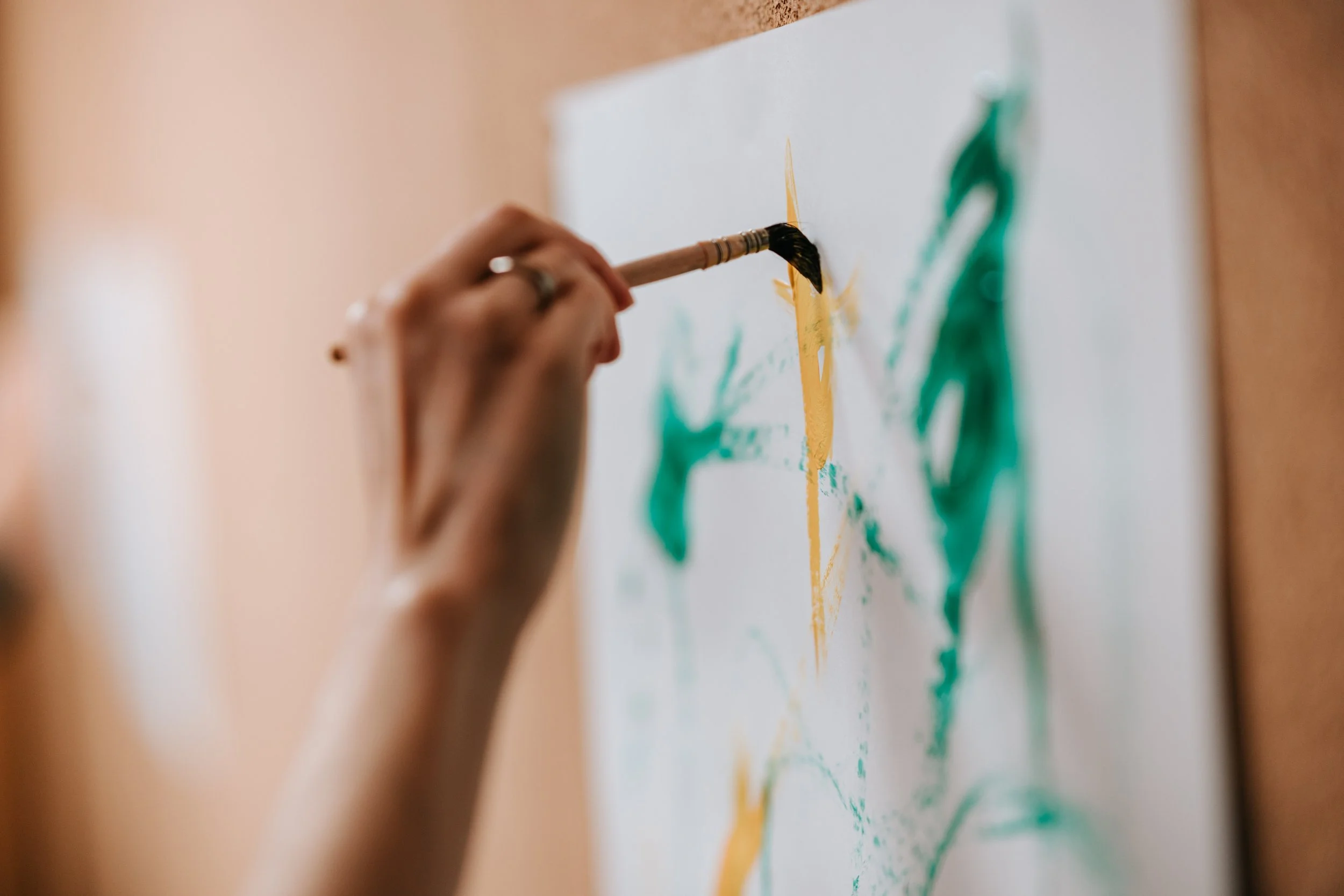 Handen aan het werk met verf en papier in het atelier.