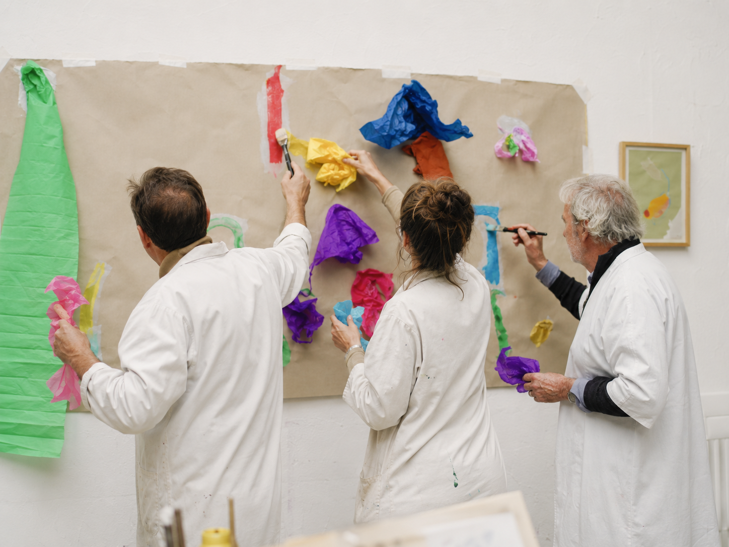 Doctors participating in a collective paper and colour work at the studio wall.