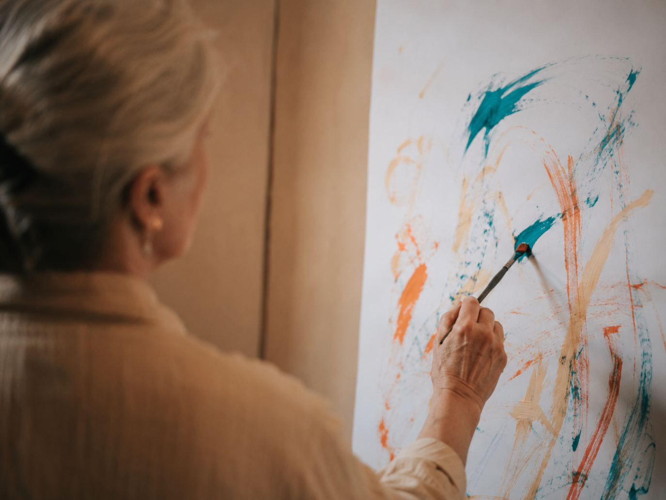Hands of participants working together on a large collective canvas with ochre, clay red and black paint in the ARTKOM atelier.